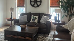 A living room with a brown leather sofa, a wooden coffee table, and a large decorative wheel on the wall.