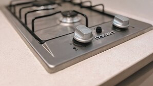 A kitchen with a gas stove, a wall-mounted oven, and a backsplash.