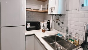 A modern kitchen with white cabinets, a stainless steel sink, a coffee maker, and a microwave.