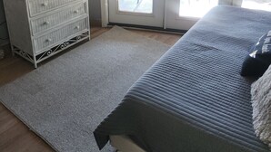 A bedroom with a bed, a dresser, a TV, and a sliding glass door leading to an outdoor patio.
