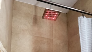 A shower area with a rain showerhead, tiled walls, and a shower curtain.