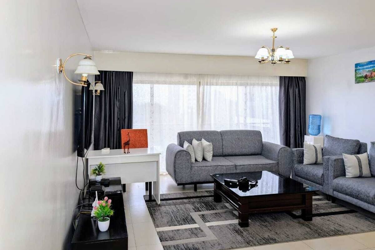 Ein modernes Wohnzimmer mit grauem Sofa, einem Couchtisch, einem weißen Schreibtisch und einer schwarzen Lampe.