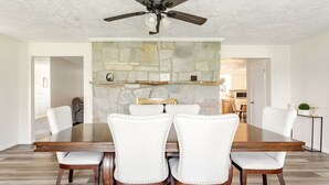 A dining room with a stone fireplace, white upholstered chairs, and a wooden table. - The place of possibilities with amazing heated pool. (Pulaski)