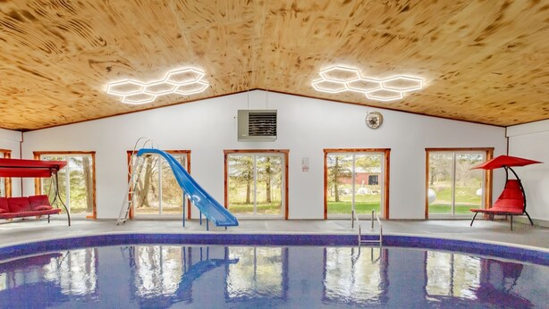 An indoor swimming pool with a wooden ceiling, a blue slide, and red seating areas. - The place of possibilities with amazing heated pool. (Pulaski)
