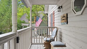 A wooden porch with a bench and a flag.