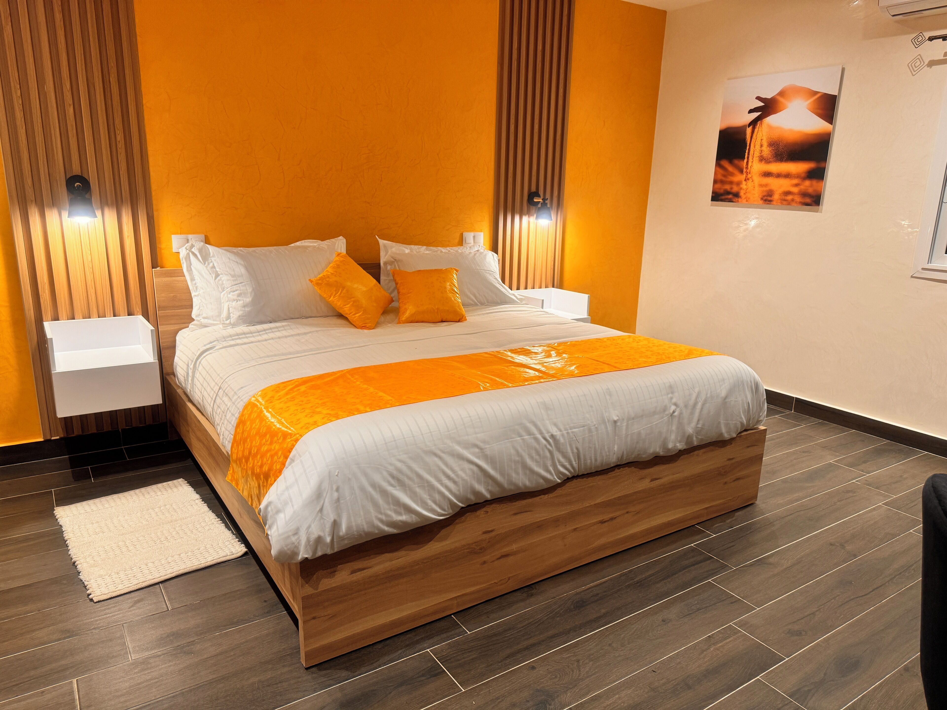 Een moderne slaapkamer met een houten bedframe, wit beddengoed en oranje accenten.