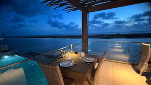 An outdoor dining area with a glass table overlooking the sea, equipped with wicker chairs and a glass pool. - La Parenthèse (Mbodiène)