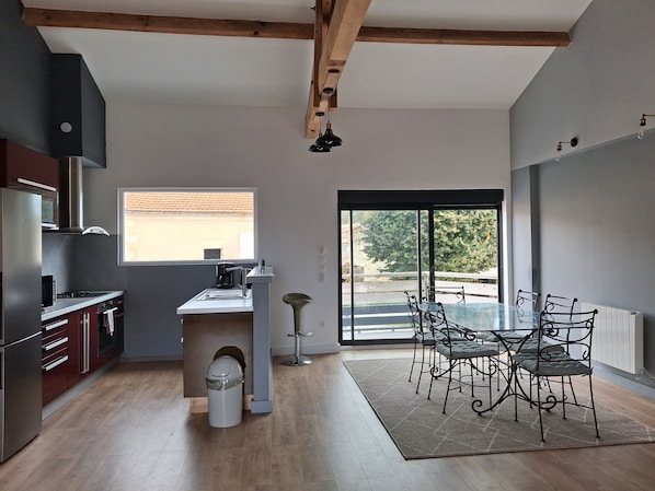 A modern kitchen with a built-in stove, a sink, and a window overlooking a garden.