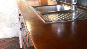 A kitchen with a stainless steel sink, wooden countertop, and a brick wall. - house for two with a private terrace located directly on the beach, town Hvar (Hvar)