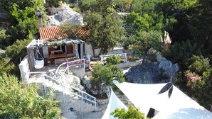 A rustic stone building with a red-tiled roof, a wooden bench, and a hanging chair. - house for two with a private terrace located directly on the beach, town Hvar (Hvar)