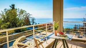Un balcón con piscina de piedra, una silla y una mesa con una planta y un libro.