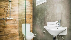 Un baño con cabina de ducha de vidrio, inodoro y lavamanos blancos.