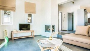Una sala de estar moderna con un sofá, televisor y una mesita con un florero.