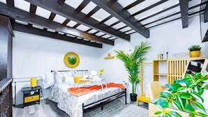Un dormitorio con cama, mesita de noche y una planta grande en maceta.