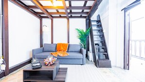 Una sala de estar moderna con un sofá gris, una mesa de centro y una escalera que sube a un nivel superior.