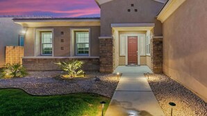 A modern two-story house with a stone facade, a front entrance with a door, and a well-lit driveway. - Lakeside Escape: Game Room W/ AC (Indio)