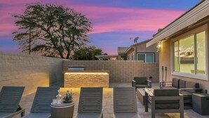 An outdoor patio with lounge chairs, a stone wall, and a built-in fire feature. - Lakeside Escape: Game Room W/ AC (Indio)