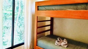 A bunk bed with a ceiling fan, a window with curtains, and a view of trees outside.
