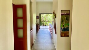 A hallway with a wooden door, a bench, and a painting on the wall.