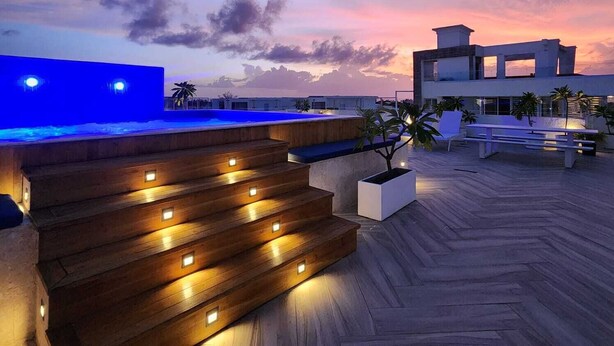 A rooftop terrace with a pool, wooden steps, and seating areas. - All Seasons Hotel Bayahibe (San Rafael del Yuma)