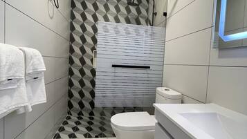 A modern bathroom with a geometric-patterned shower wall, a toilet, and a bathtub.