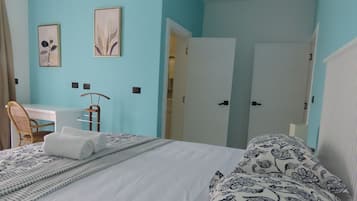 A bedroom with a bed, a desk, and a chair. There are two doors leading to other rooms.