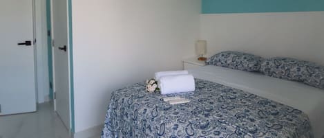 A bedroom with a bed, a nightstand, a lamp, and a door.