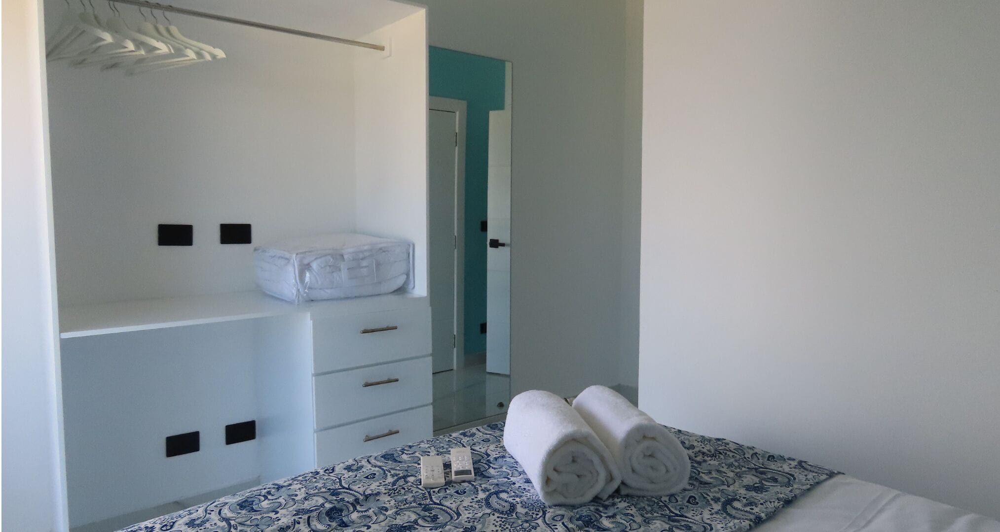 Une chambre à coucher avec un lit, une armoire et une salle de bain visible à travers une porte ouverte.