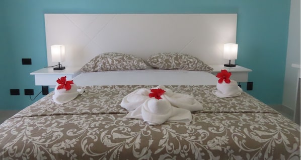 A hotel room with a bed, two nightstands, and two bedside lamps. - All Seasons Hotel Bayahibe (San Rafael del Yuma)
