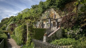 A stone building with a wooden fence, surrounded by lush greenery and a clear sky. - House for 6 people ideally located, close to many leisure activities (La Chapelle-Huon)