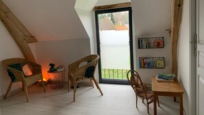 A cozy attic room with two wicker chairs, a small table, and a bookshelf. - House for 6 people ideally located, close to many leisure activities (La Chapelle-Huon)