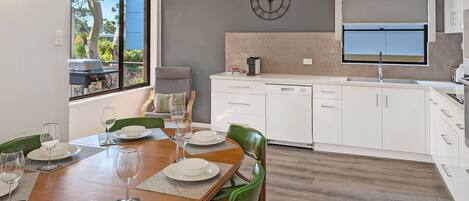 A modern kitchen with white cabinets, a built-in oven, and a window above the sink.