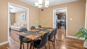 A dining area with a wooden table, black chairs, and a chandelier. There is a kitchen in the background with stainless steel appliances. - Serene Retreat Near Fort Campbell and Casino -  Family and Pet Friendly (Clarksville)