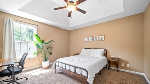 A bedroom with a bed, a desk, a chair, a ceiling fan, a window, and a potted plant. - Serene Retreat Near Fort Campbell and Casino -  Family and Pet Friendly (Clarksville)
