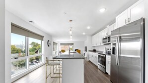 Una cocina moderna con armarios blancos, electrodomésticos de acero inoxidable y una isla grande.