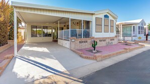 A single-story house with a covered porch, a small garden with a cactus, and a garage. - Recliners! Large Az Room - Adult 55+ Activities Galore! (Mesa)