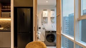 A modern kitchen with a black refrigerator, a microwave, and a Bosch washing machine. - 3BR Penthouse with Jacuzzi & A/C in El Poblado (Medellín)
