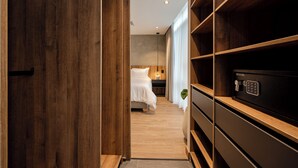 A hotel room with a wooden floor, a bed with white bedding, a nightstand, and a safe. - 3BR Penthouse with Jacuzzi & A/C in El Poblado (Medellín)