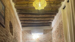 Una habitación acogedora con una cama, una mesa con un vaso y una botella, y una lámpara colgante.