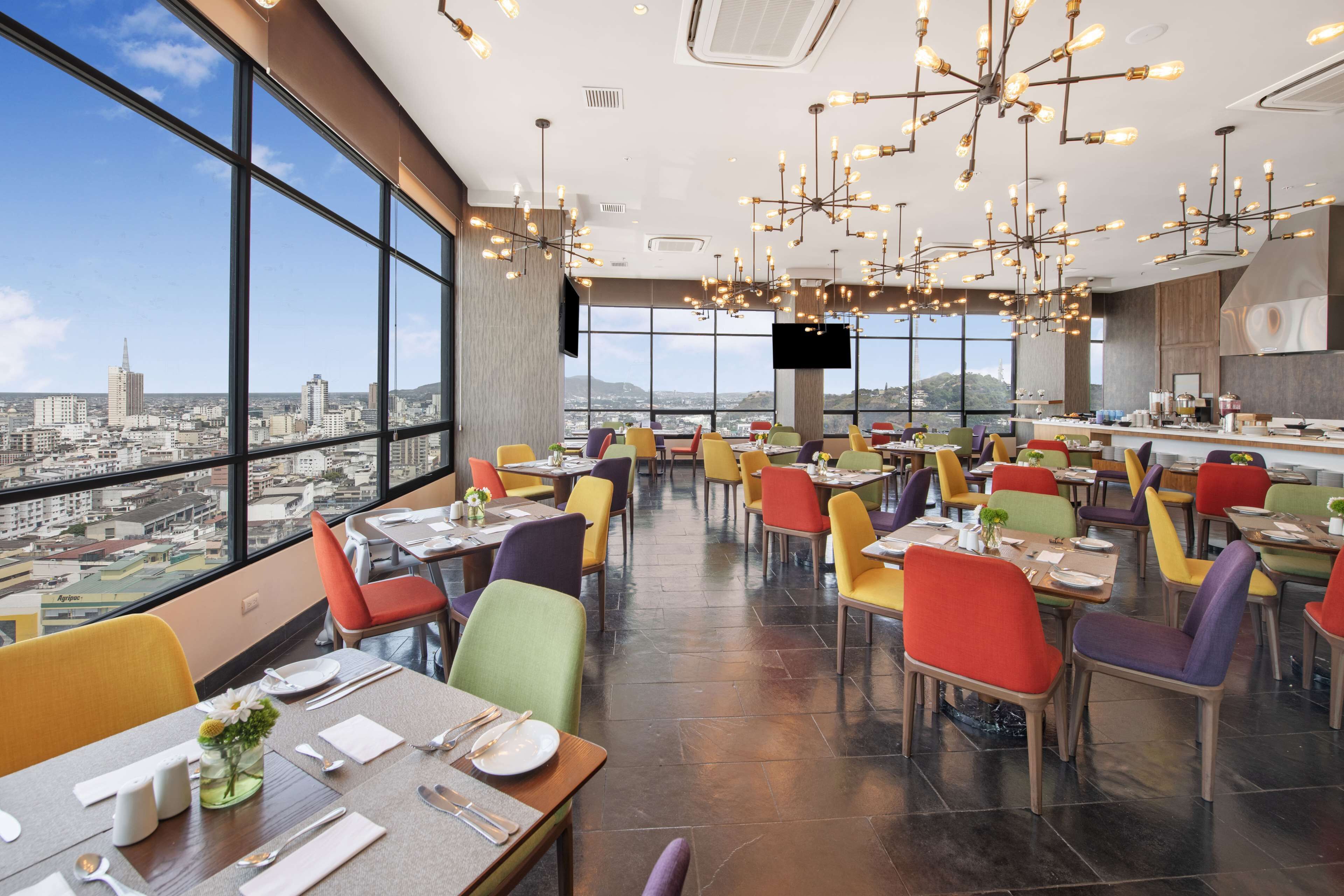 Un restaurante moderno con vistas panorámicas de la ciudad, varias zonas de comedor e iluminación contemporánea.
