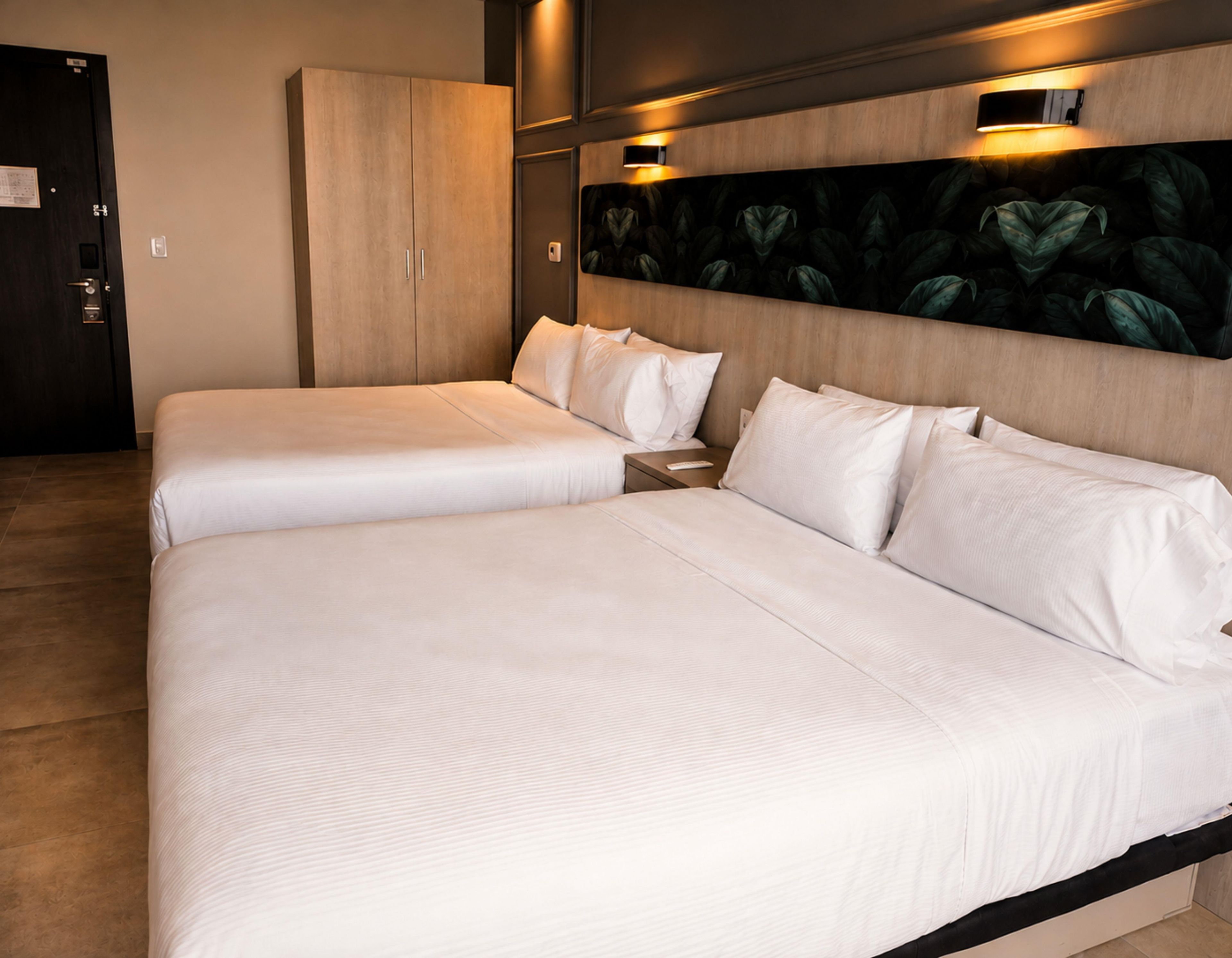 Una cama doble con cabecera de madera, una mesita de noche y un aplique de pared.