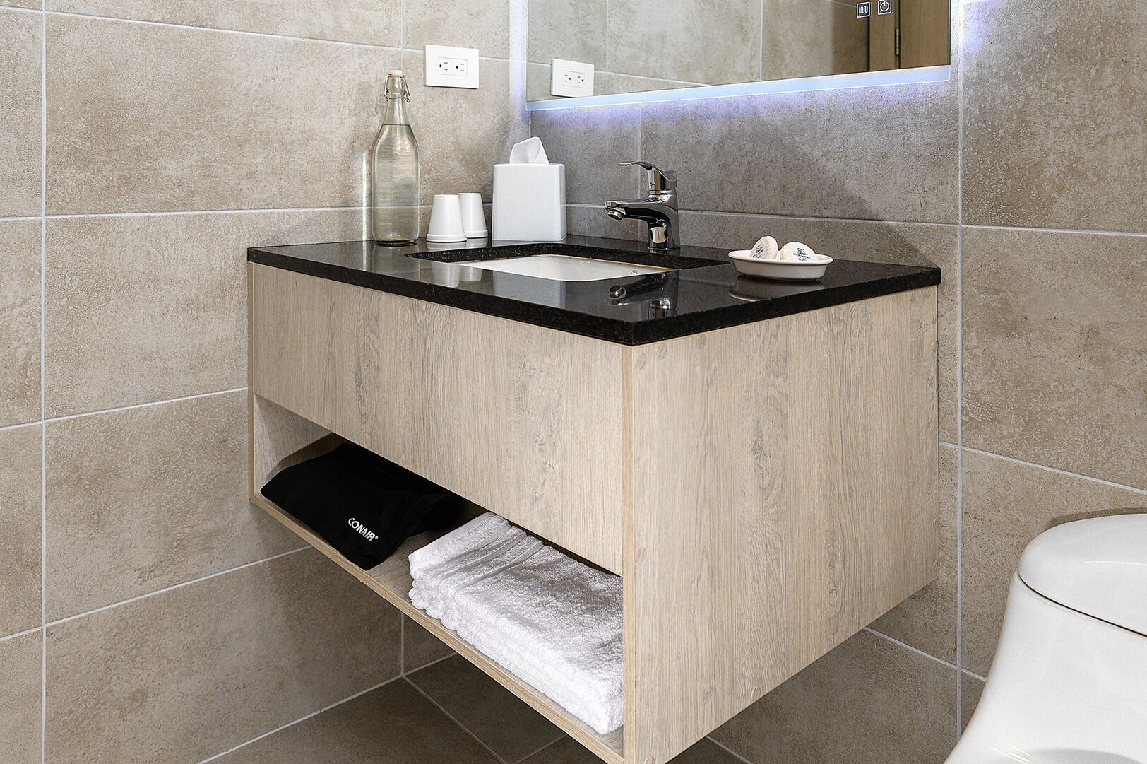 Un baño moderno con lavamanos de encimera negro, un espejo y un perchero para toallas.