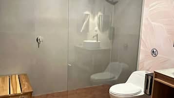 A modern bathroom with a glass-enclosed shower, a wooden vanity, and a white toilet.