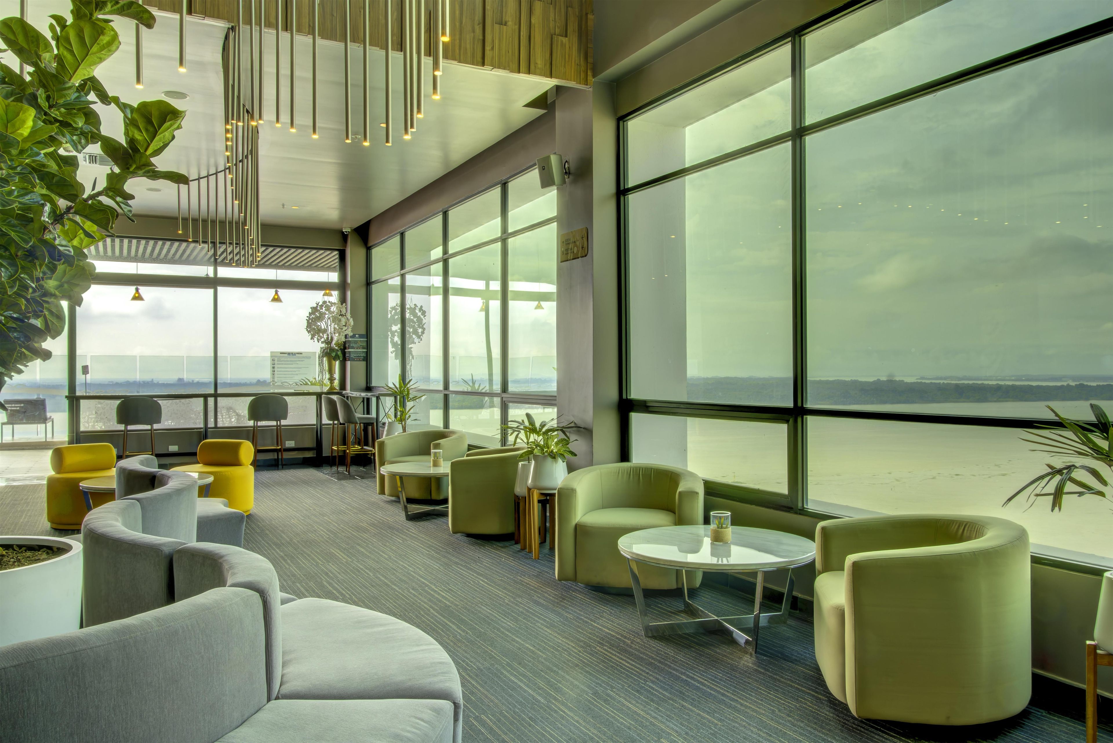 Un amplio salón con grandes ventanales, asientos cómodos y vistas al exterior.