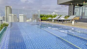 Una piscina a sfioro sul tetto con poltrone relax e vista sulla città.