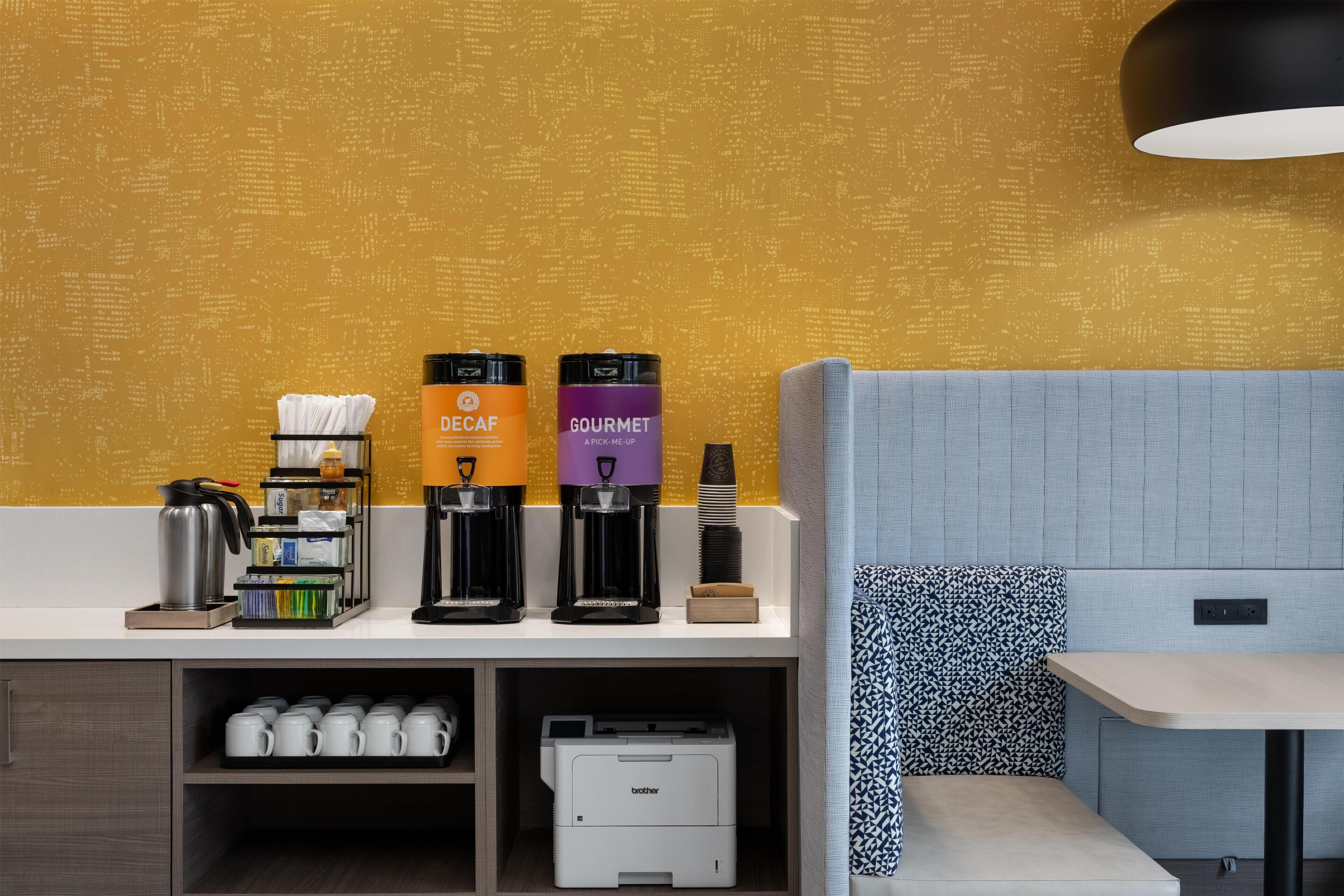 A kitchenette with coffee makers, a coffee machine, and a printer on a counter.