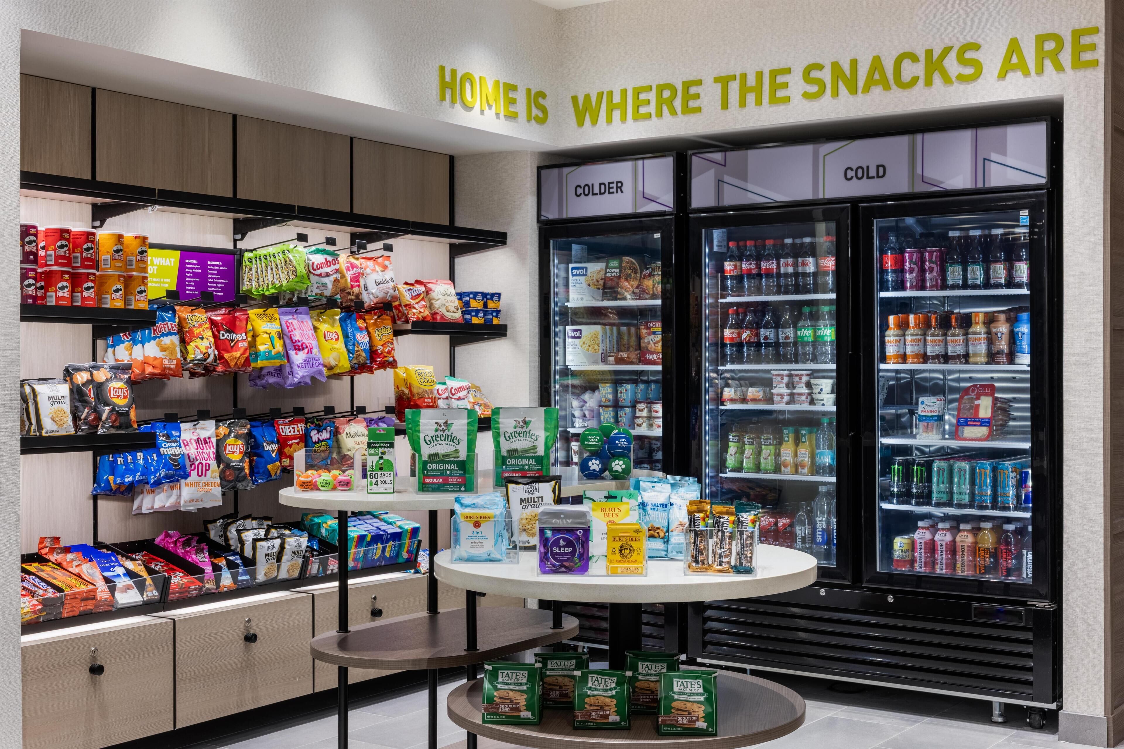 A snack display with various packaged snacks and a beverage cooler.