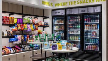 A snack display with various packaged snacks and a beverage cooler.