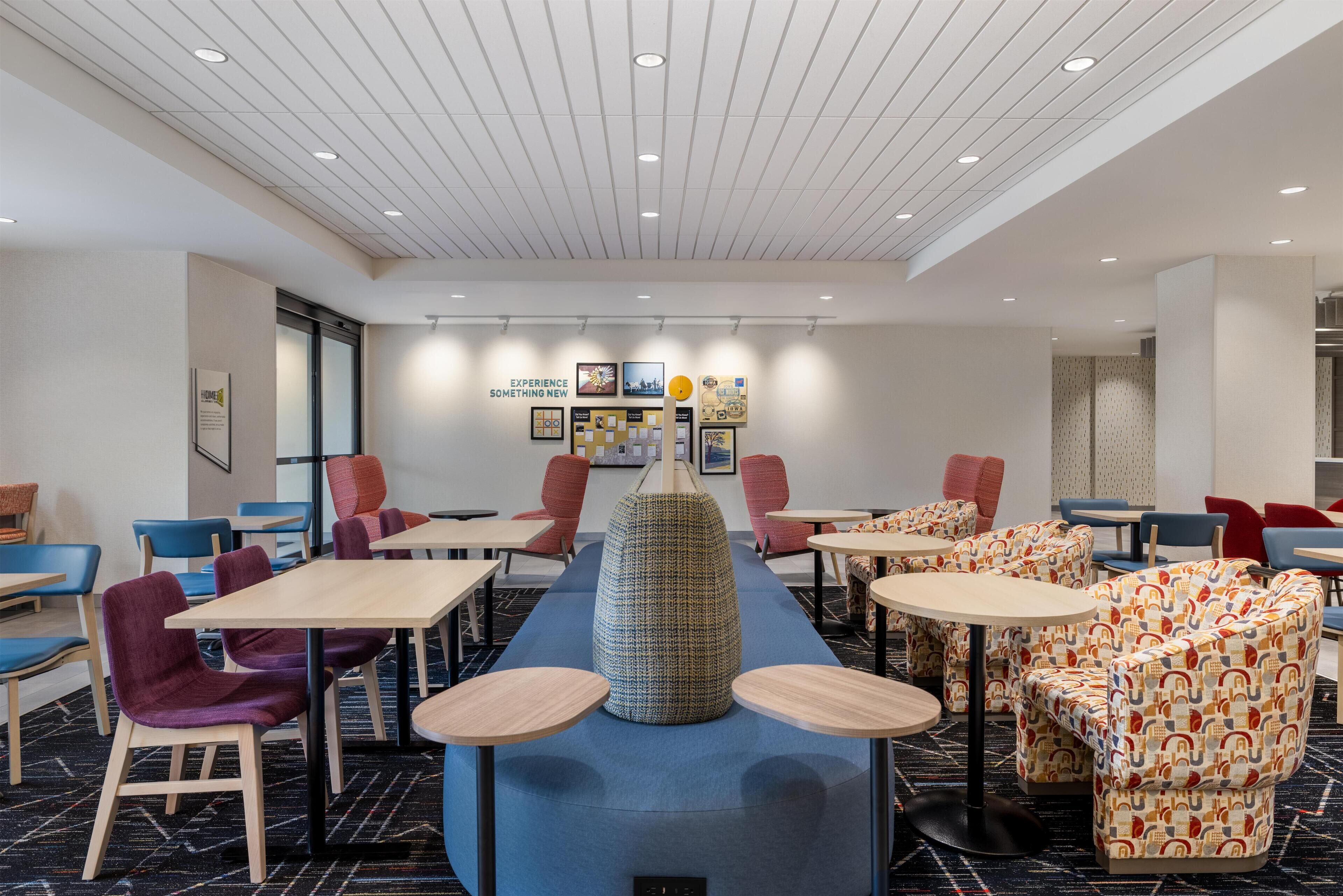 A modern hotel lobby with a long counter, multiple seating areas, and a ceiling with recessed lighting.