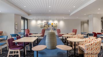 A modern hotel lobby with a long counter, multiple seating areas, and a ceiling with recessed lighting.